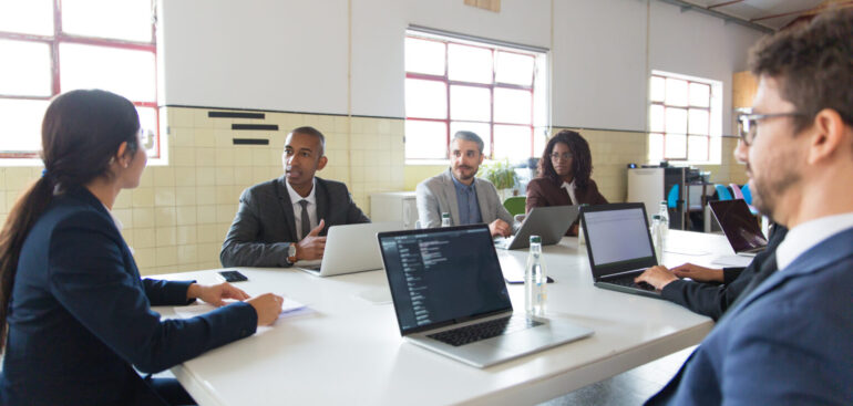Business team discussing strategy in a meeting with laptops in a modern office