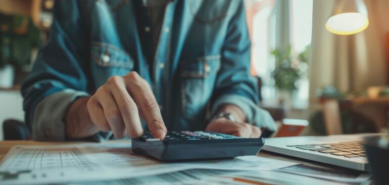 Person using a calculator while reviewing financial documents at a desk